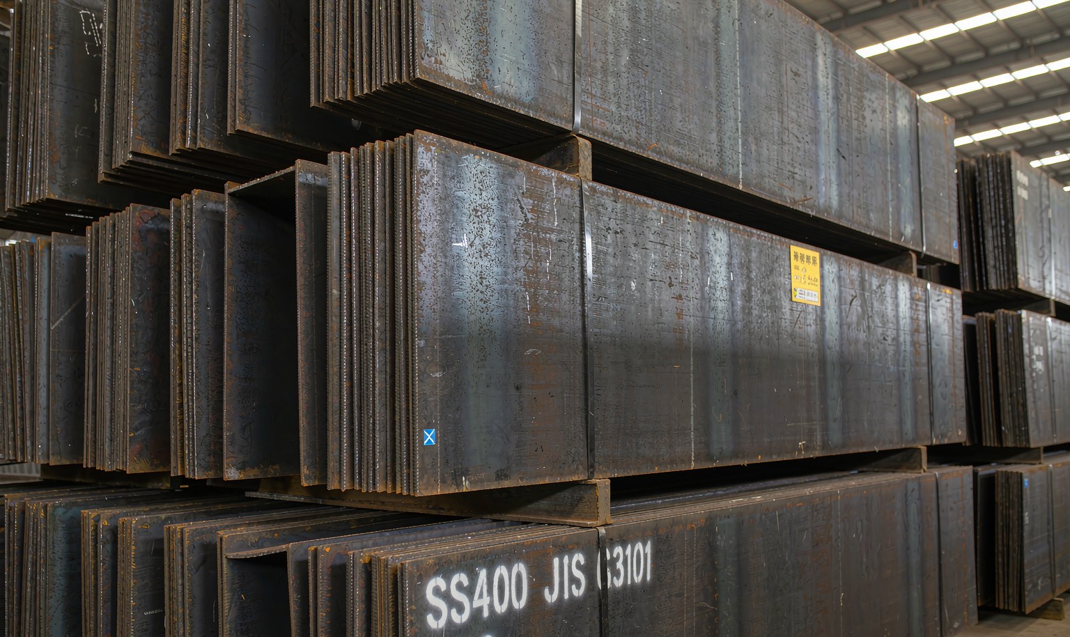 Stacked S275JR structural steel beams in a warehouse